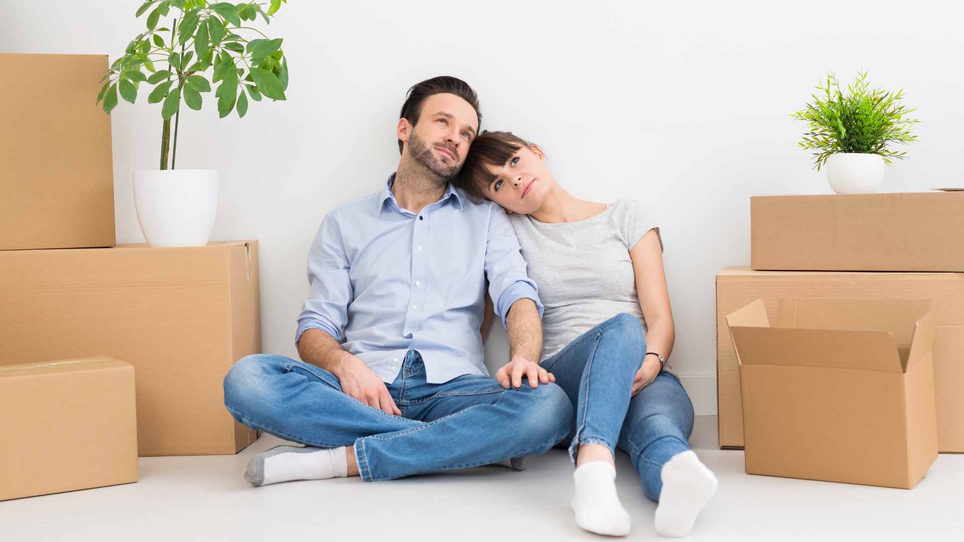 A man and woman sitting on the floor surrounded by boxes